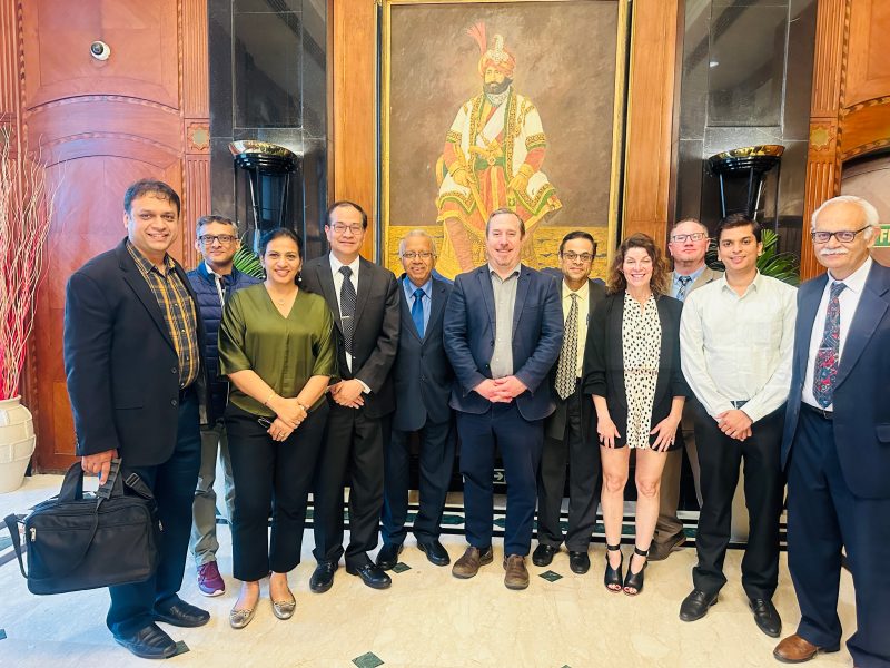 A group of 11 people posing for a picture in a hotel lobby in India