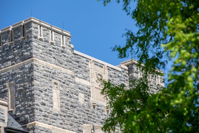 A grey Hokie Stone building with a tree branch spanning across the image. 