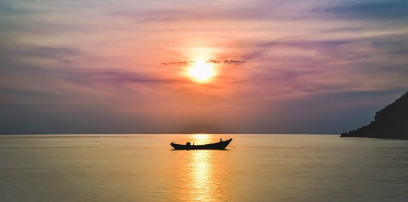 photo of a lake at sunset with with a small empty boat